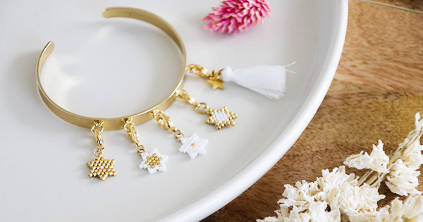 Bracciale a tessitura dorata e pompon Bracciale a tessitura dorata e pompon