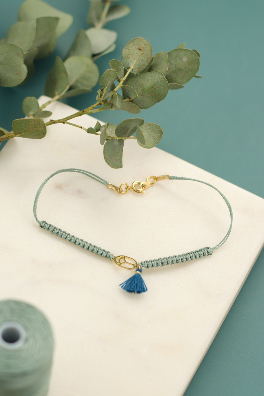 Schema Fai da te Crea un braccialetto macramè con intercalare verde acqua e pompon Schema Fai da te Crea un braccialetto macramè con intercalare verde acqua e pompon