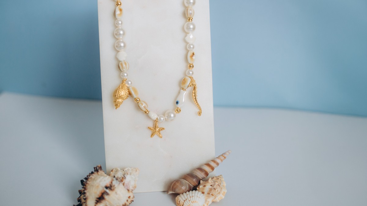 Collana con perle di ceramica, perle di madreperla e ciondoli marini Collana con perle di ceramica, perle di madreperla e ciondoli marini